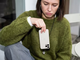 Грустная девушка держит телефон перевёрнутым