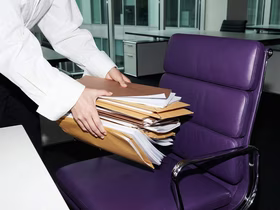 Человеческие руки кладут стопку папок на фиолетовый диван