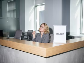 Женщина сидит за стойкой с надписью "Кредит"