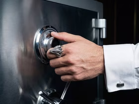 Мужская рука с кольцом дракона открывает сейф