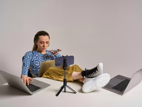 Девушка сидит с двумя ноутбуками и двумя телефонами