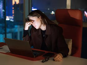 Девушка закрывает глаза и сидит перед ноутбуком