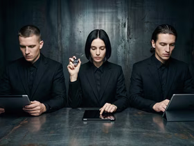 Три человека сидят за столом в тёмной комнате