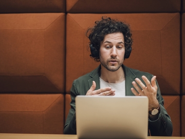 Мужчина в наушниках сидит перед ноутбуком