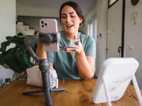 Женщина сидит и снимает ролик про косметику на телефон