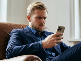 Мужчина хмурится и смотрит в телефон