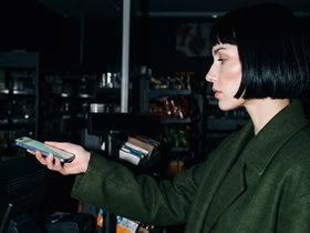 Девушка держит в вытянутой руке телефон