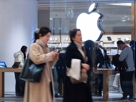 девушки азиатской внешности идут рядом с магазином Apple