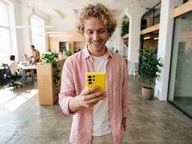 мужчина смотрит в жёлтый телефон