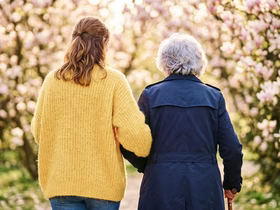 Девушка помогает идти пожилой женщине