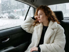 Девушка сидит в машине и смотрит в окно