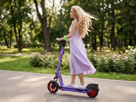 Девушка в платье едет на самокате