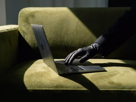 Рука в чёрной перчатке печатает на ноутбуке