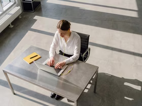 Женщина сидит за столом и смотрит в ноутбук