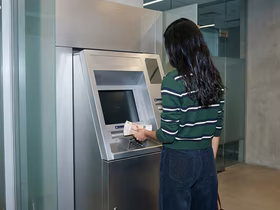 Девушка с деньгами перед банкоматом