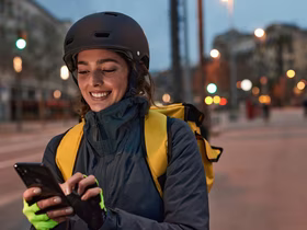 Девушка курьер улыбается и смотрит в телефон