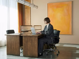 Женщина сидит за столом и смотрит в ноутбук