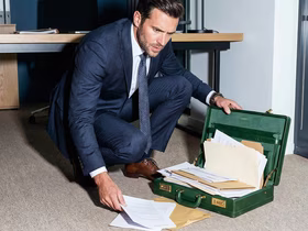 Мужчина перед портфелем, из которого выпали документы
