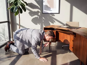 Мужчина в офисном костюме с лупой рассматривает пол