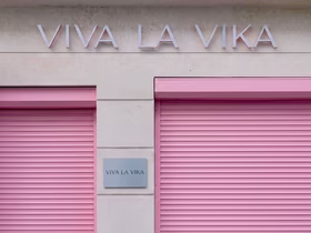 Закрытые розовые рольставни магазина VIVA LA VIKA с вывеской бренда на фасаде здания