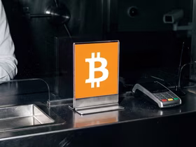 На прилавке стоит табличка с логотипом Биткойна