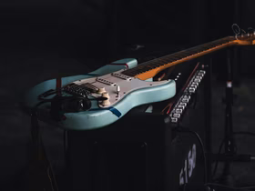 Голубая электрогитара Fender Stratocaster лежит на комбоусилителе
