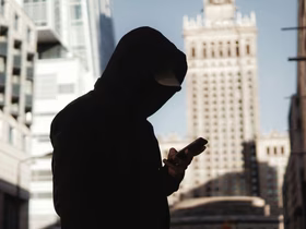 Парень в черном худи стоит на улице