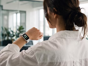 Девушка в белой рубашке смотрит в экран фитнес-браслета Redmi Band 4