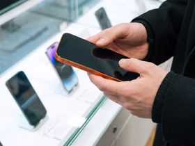 Человек держит в руках оранжевый смартфон