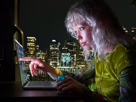 Девушка использует MacBook Pro с сенсорным экраном на фоне ночного города