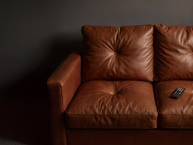 На коричневом диване лежит пульт от телевизора