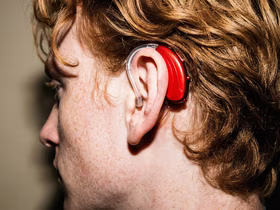 красный слуховой аппарат на ухе