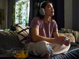 Девушка в наушниках играет на игровой консоли