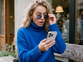 Девушка в синем свитере со смартфоном и в очках