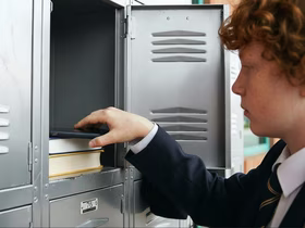 Школьник убирает телефон в шкафчик