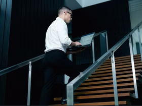 Мужчина поднимается по лестнице и печатает в ноутбуке