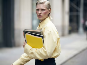 Девушка в желтой куртке держит в руках папки с бумагами