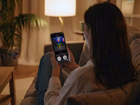 Девушка на диване смотрит в открытое на смартфоне приложение КИОН