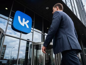 Мужчина в костюме идет к офису с логотипом VK