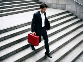 Мужчина с красным чемоданом спускается по лестнице