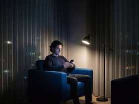 Мужчина смотрит в телефон, сидя в кресле