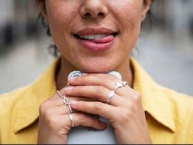 девушка держит телефон и показывает язык