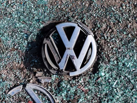 Логотип Volkswagen лежит на земле и разбитом стекле после ДТП