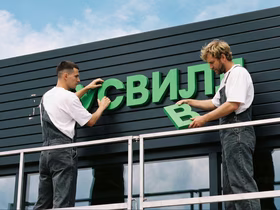 Рабочие устанавливают вывеску магазина «ВкусВилл»
