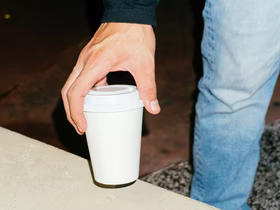 Рука держит стаканчик с кофе навынос