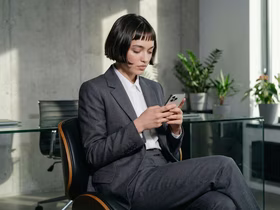 Девушка в деловом костюме печатает в телефоне