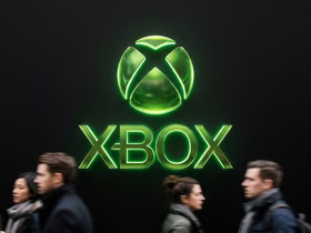 На тёмном фоне светится зелёный логотип Xbox, а внизу мимо него проходят люди