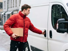 Курьер несет посылку к фургону