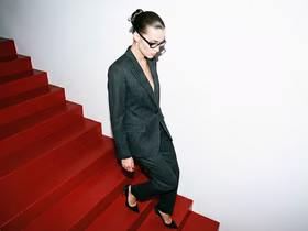 Женщина в деловом костюме спускается по красной лестнице