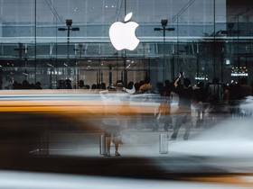 Логотип Apple на офисном здании и толпа людей